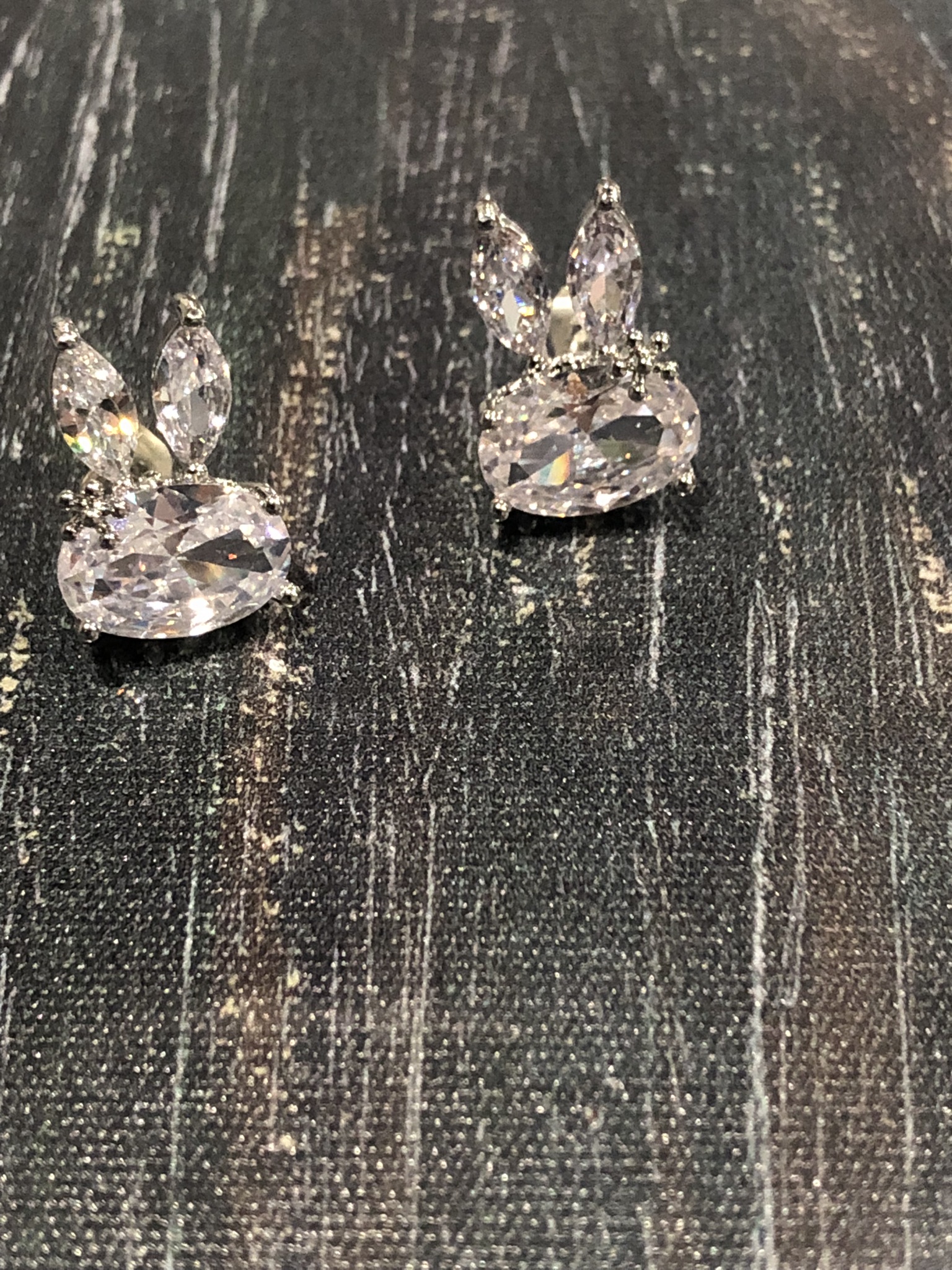 A close view of Rochel's faceted-effect drop earrings on their original dark fabric